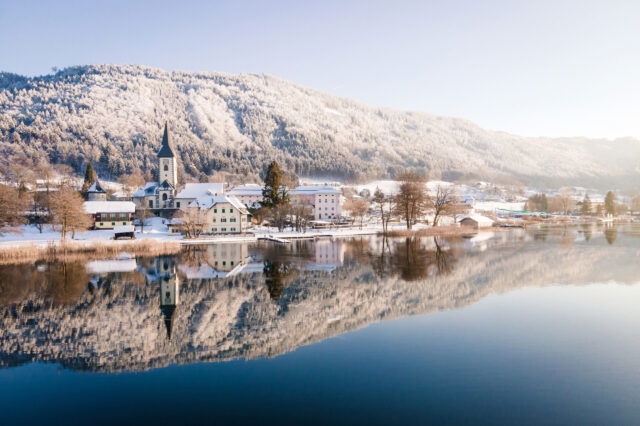 Blick auf eine Kirche am Ossiacher See in verschneiter Landschaft