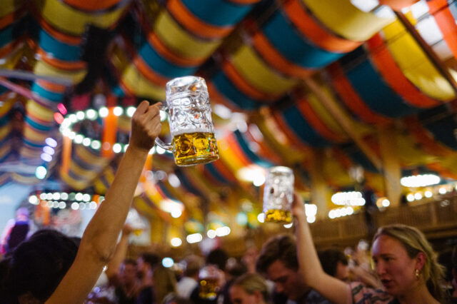 Masskrüge in einem Festzelt, die in die Höhe gehoben werden