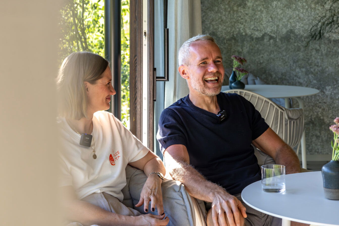 Zwei Menschen sitzen lachend im modernen, hellen Innenraum des Old School Guesthouse und genießen die entspannte Atmosphäre.