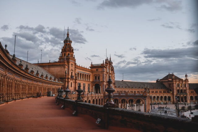 Plaza de España in Sevilla, Spanien, bei Sonnenuntergang mit rotgoldenem Licht auf den historischen Gebäuden – ein beliebtes Reiseziel für einen herbstlichen Städtetrip im Oktober in Europa.