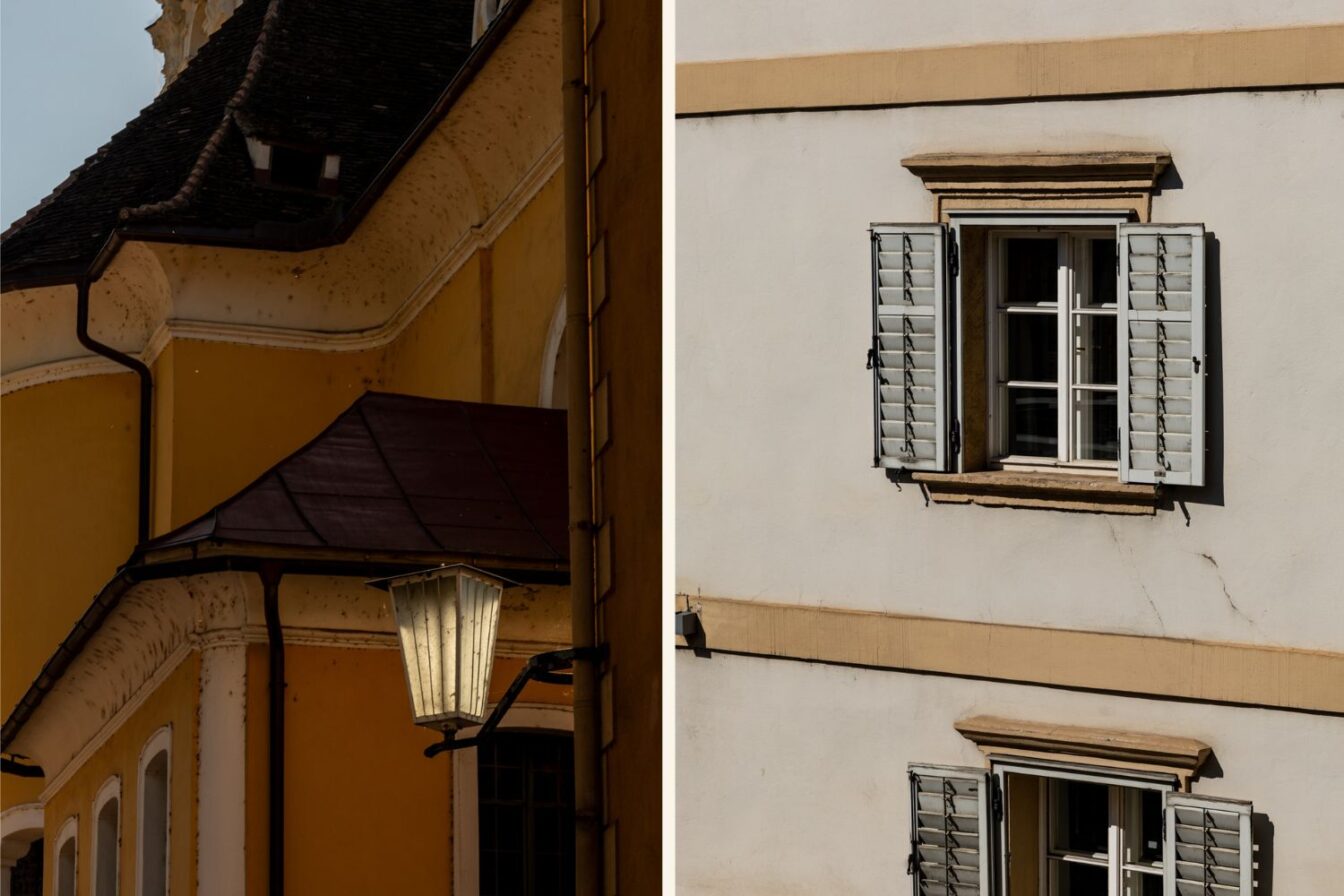 Detailaufnahme von Architektur in der Südsteiermark: gelbes Gebäude mit Laterne und weißes Haus mit geöffneten Fensterläden.