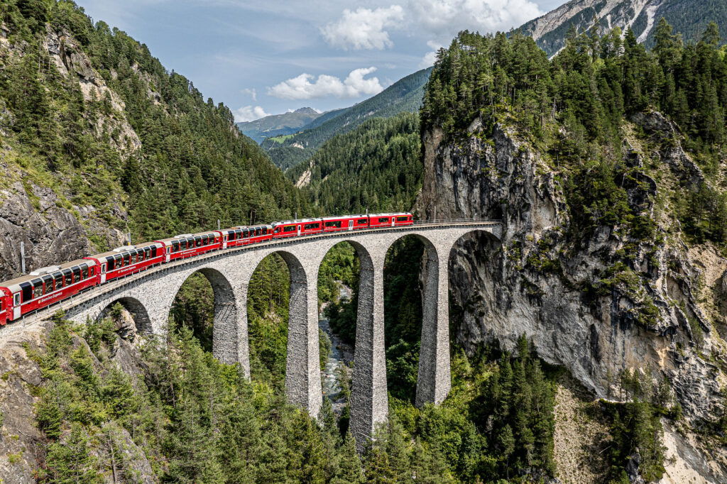 Ein Zug fährt über eine hohe Brücke in den Bergen