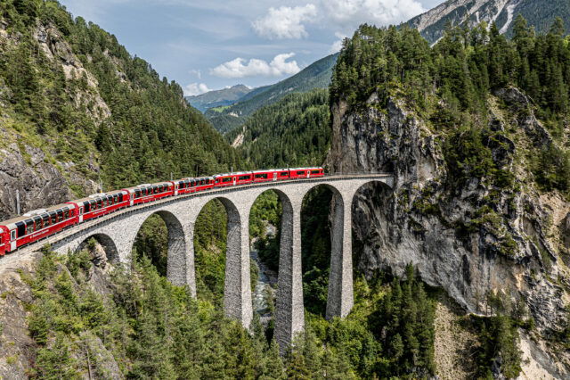 Ein Zug fährt über eine hohe Brücke in den Bergen