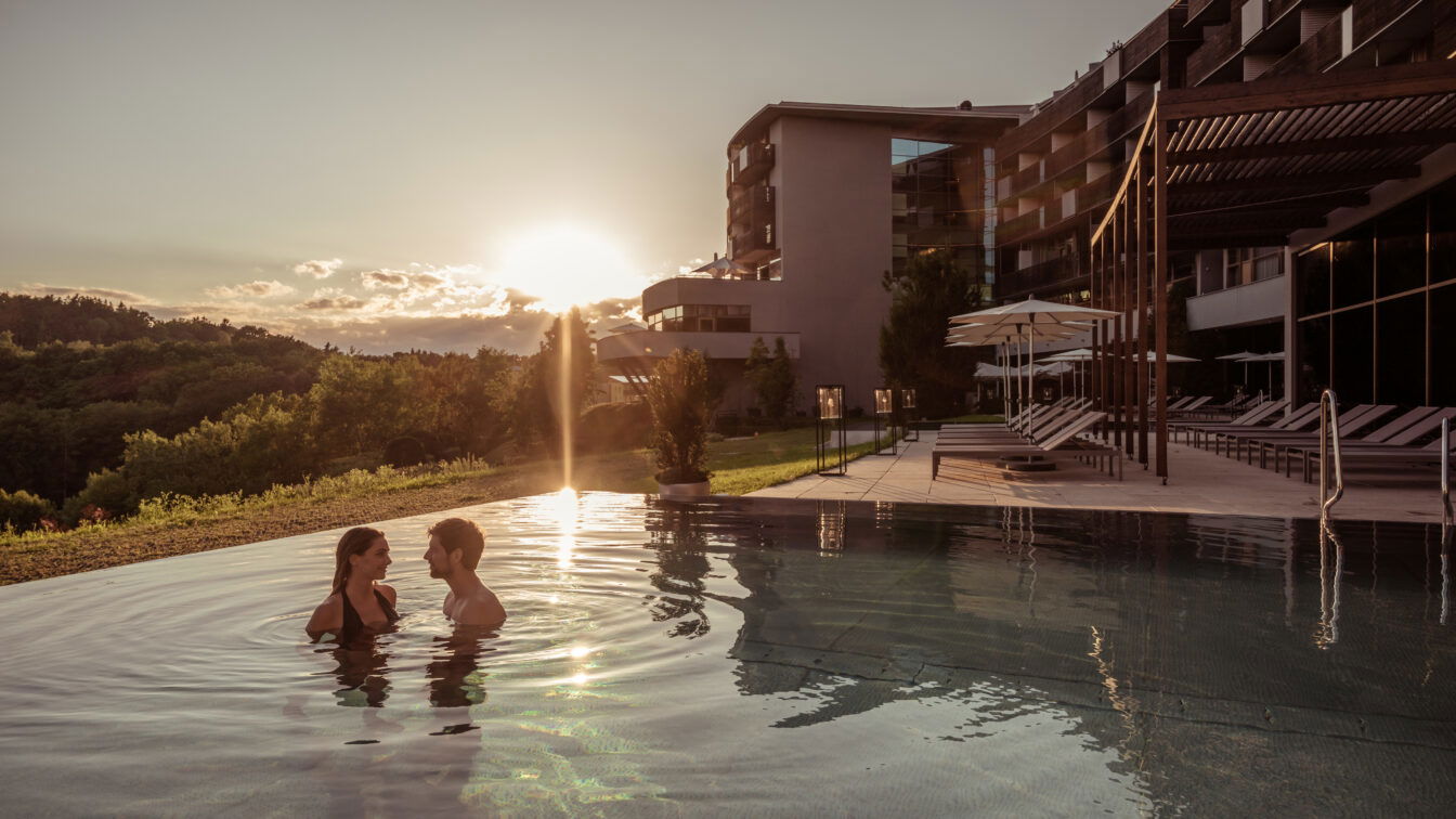 Zwei Menschen im Infinity Pool bei Sonnenuntergang