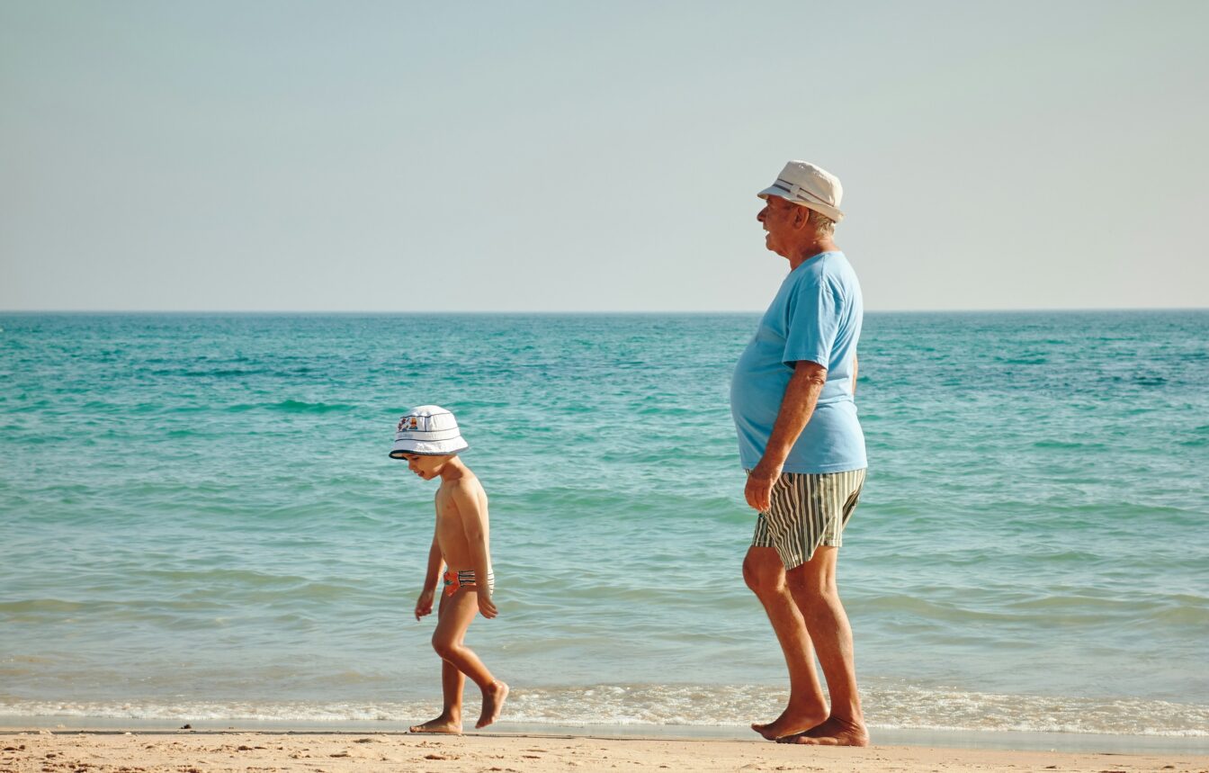 ein Großvater spaziert mit seinem Enkel am Strand