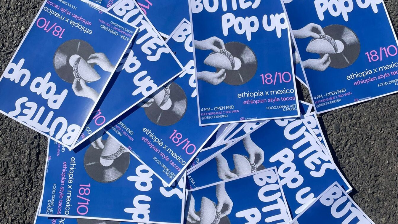 (c) Menschen für Menschen, Karlheinz Böhms Äthiopienhilfe Mehrere blaue Plakate liegen auf Asphalt verteilt. Auf den Plakaten steht in weißer Schrift ‚BUTTES Pop up‘ mit dem Datum 18/10. Darunter steht ‚ethiopia x mexico – ethiopian style tacos‘ sowie weitere Veranstaltungsinformationen. In der Mitte ist ein Schwarz-Weiß-Foto von zwei Händen, die einen Taco halten