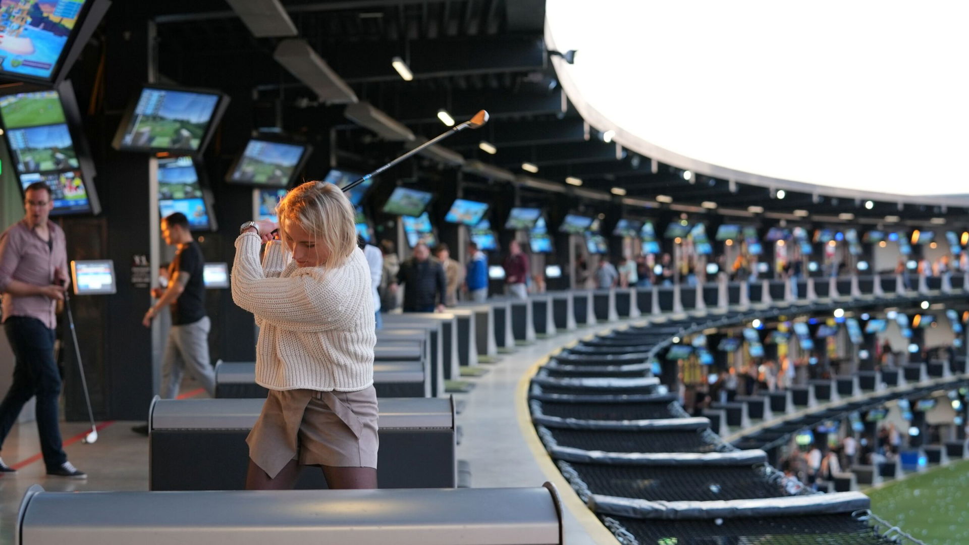 Frau beim Abschlag bei Topgolf