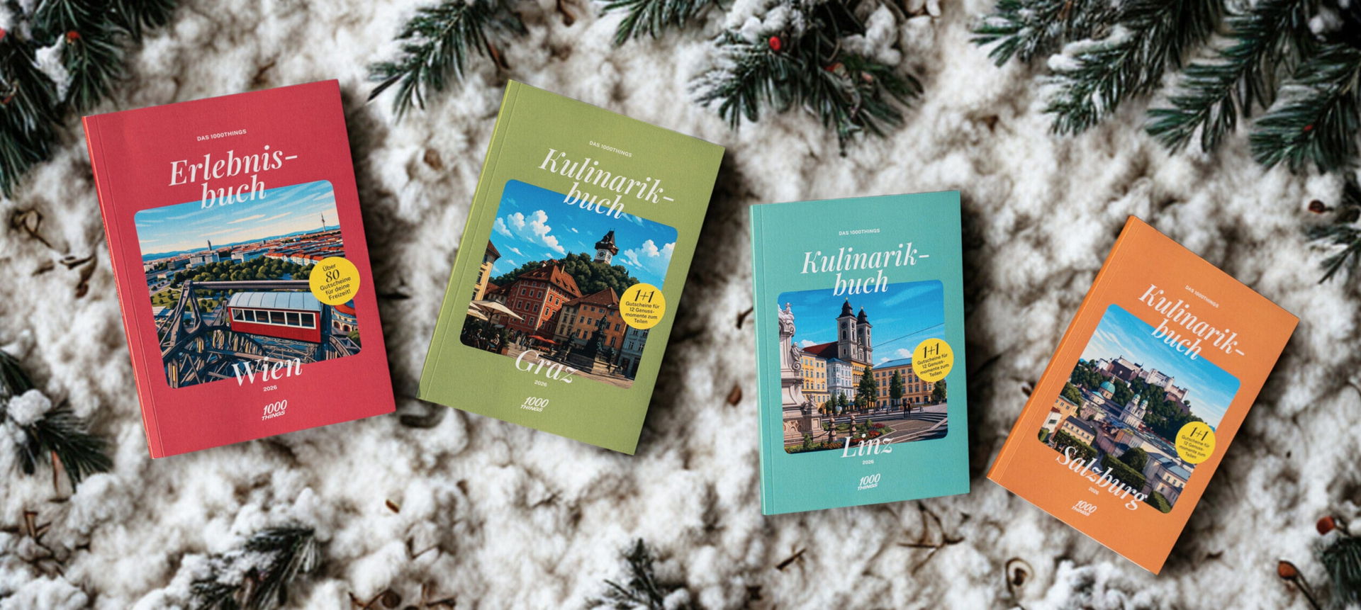 Vier 1000things Bücher – das Erlebnisbuch Wien sowie die Kulinarikbücher Graz, Linz und Salzburg – liegen auf schneebedeckten Tannenzweigen im winterlichen Setting.