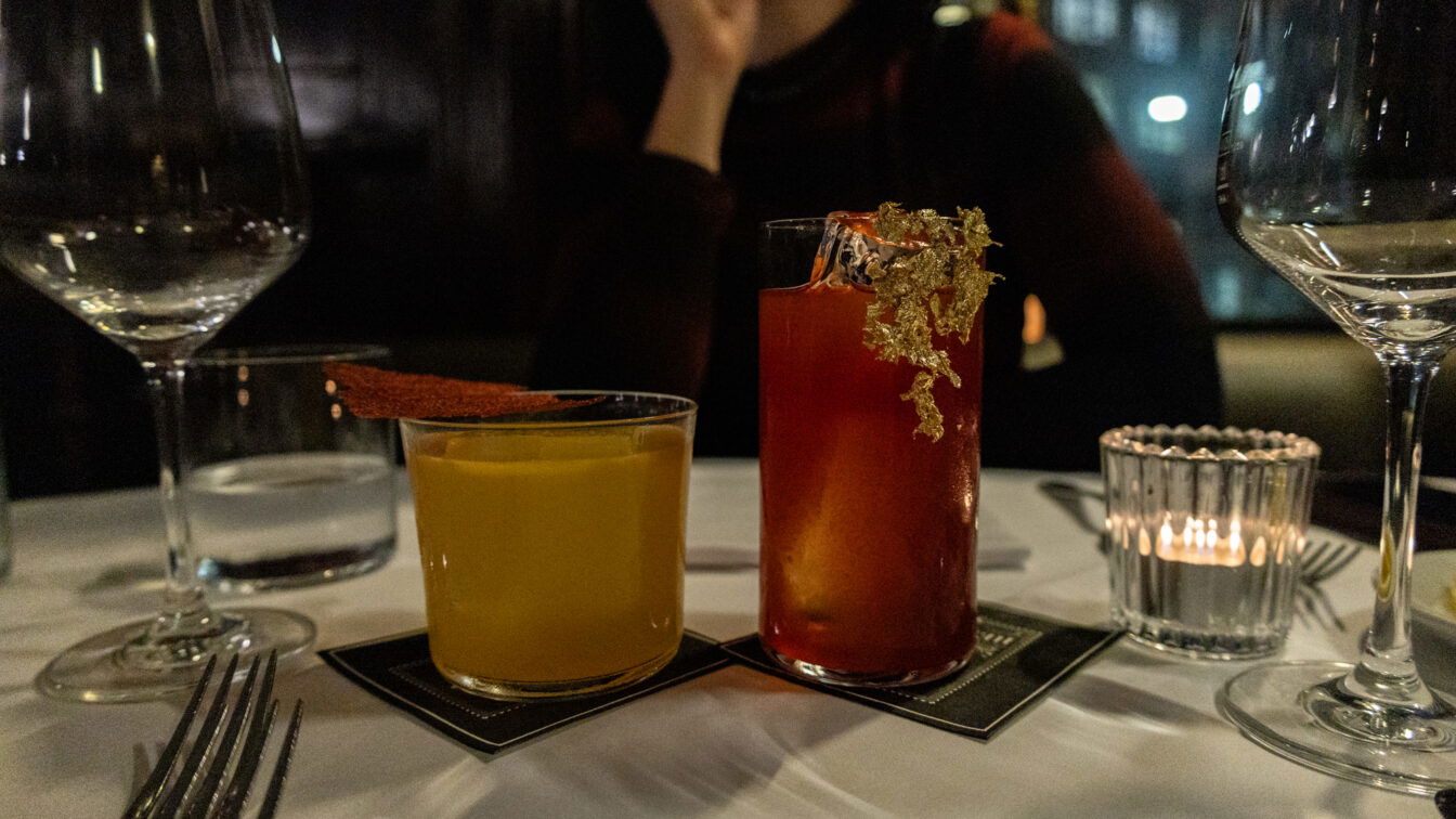 Zwei kunstvoll dekorierte Cocktails auf elegant gedecktem Tisch in einem der Restaurants Zürich außergewöhnlich – stilvolles Fine-Dining-Ambiente mit gedimmtem Licht und moderner Barkultur.