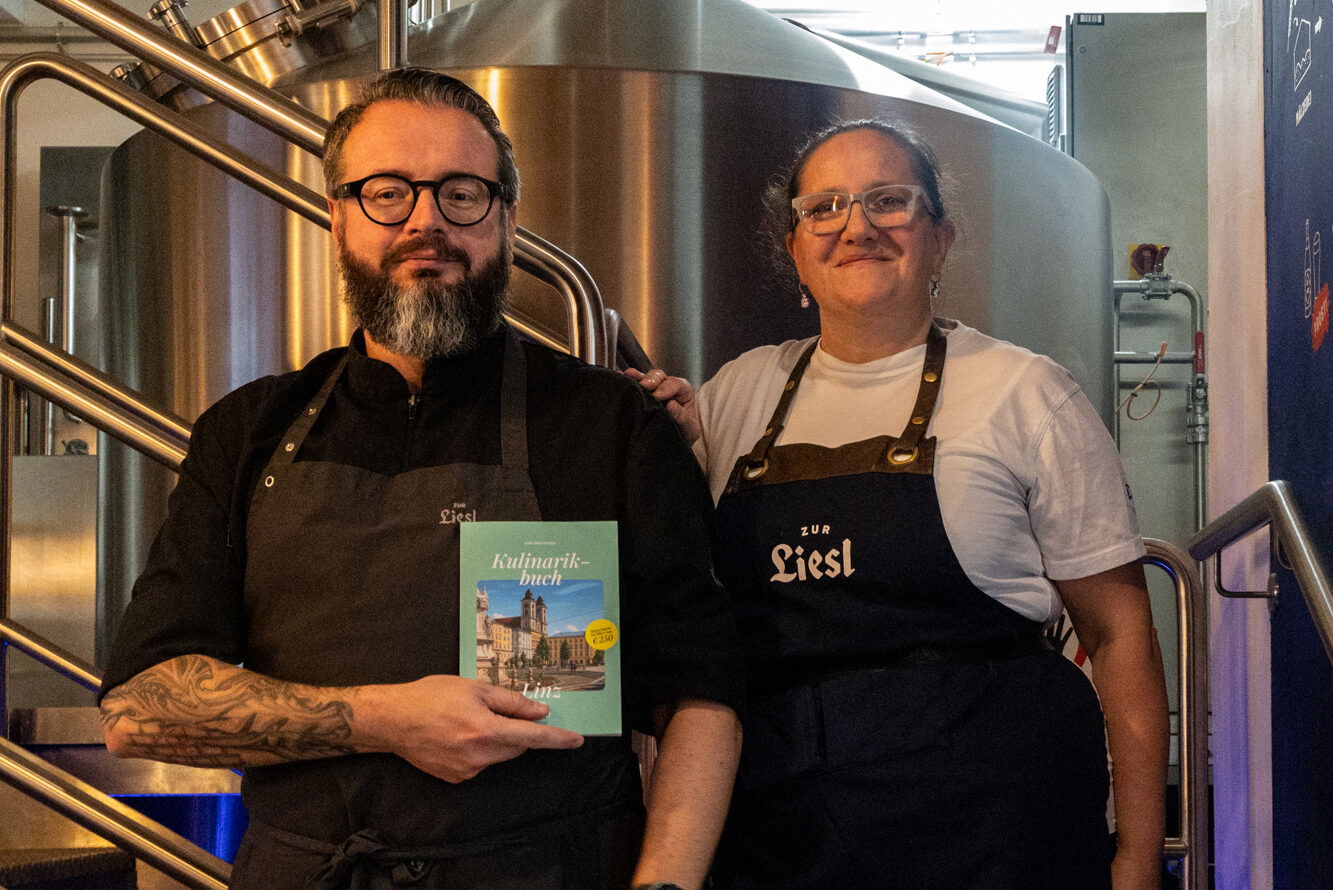 Küchenchef Dominik Jobs und Barchefin Bianca Falkner mit dem 1000things Kulinarikbuch im "Zur Liesl" in Linz