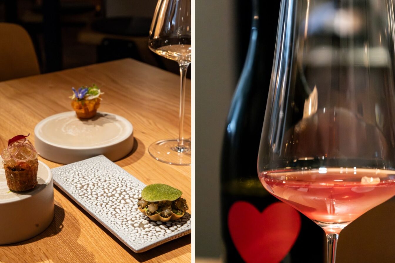 Fein angerichtete Häppchen im Matthias Berlin auf kunstvollen Tellern, begleitet von einem Glas Roséwein vor einer Flasche mit rotem Herzlabel.