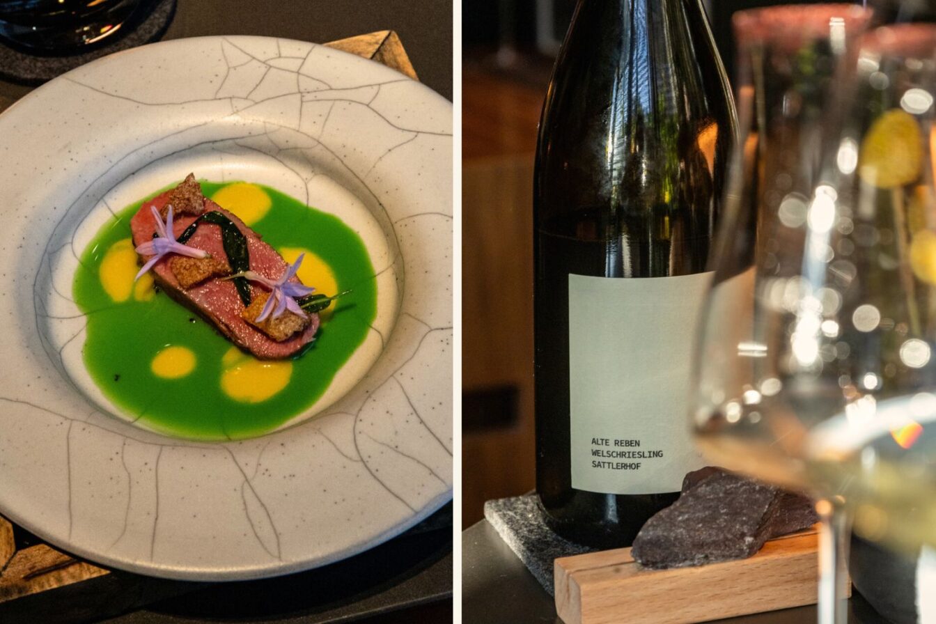 Fein angerichtetes Gourmetgericht im Restaurant Rutz Berlin: zartes Fleisch auf leuchtend grünem und gelbem Sud, garniert mit essbaren Blüten; daneben eine Flasche Welschriesling als Weinbegleitung
