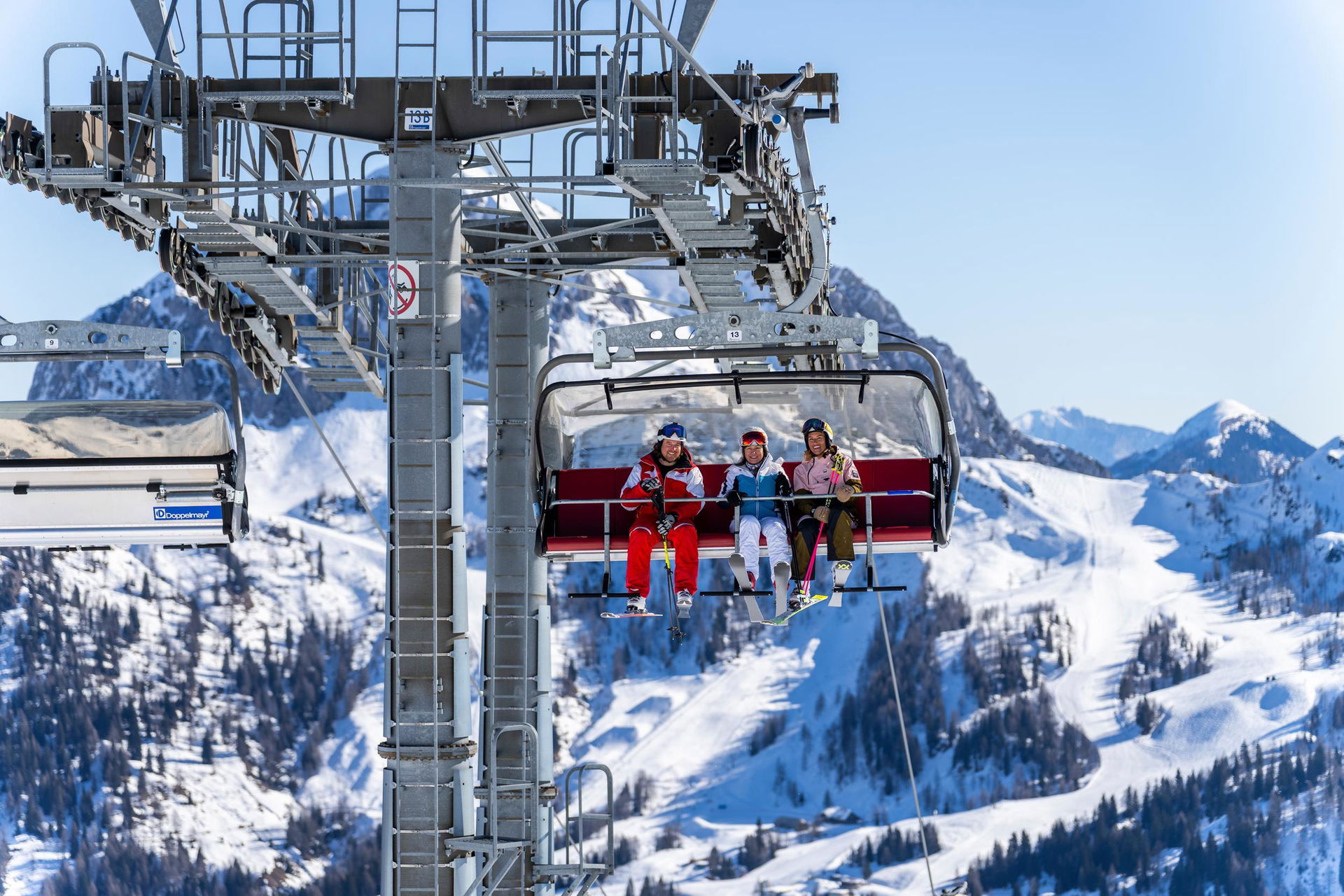 Skifahrende im Lift mit Berg im Hintergrund