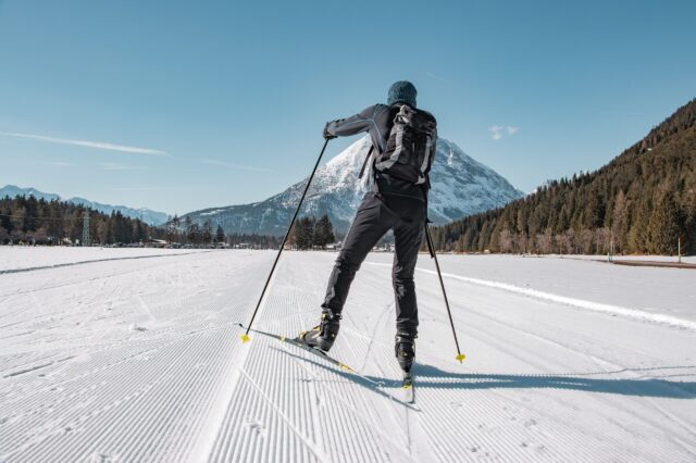 Wintersport in Österreich: Langlaufende Person vor einem Berg in Tirol