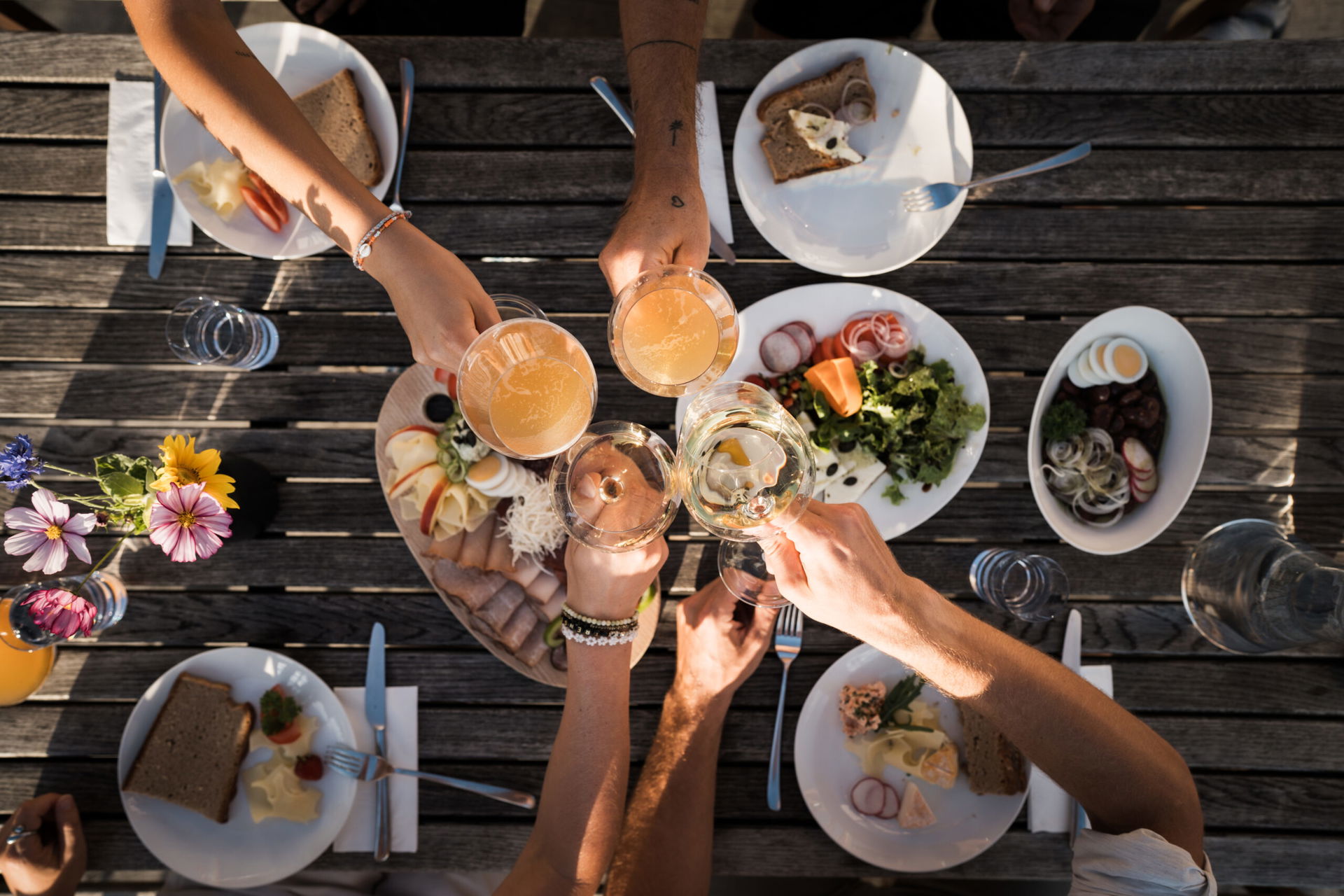 Menschen stoßen an über einem Tisch voll mit Essen