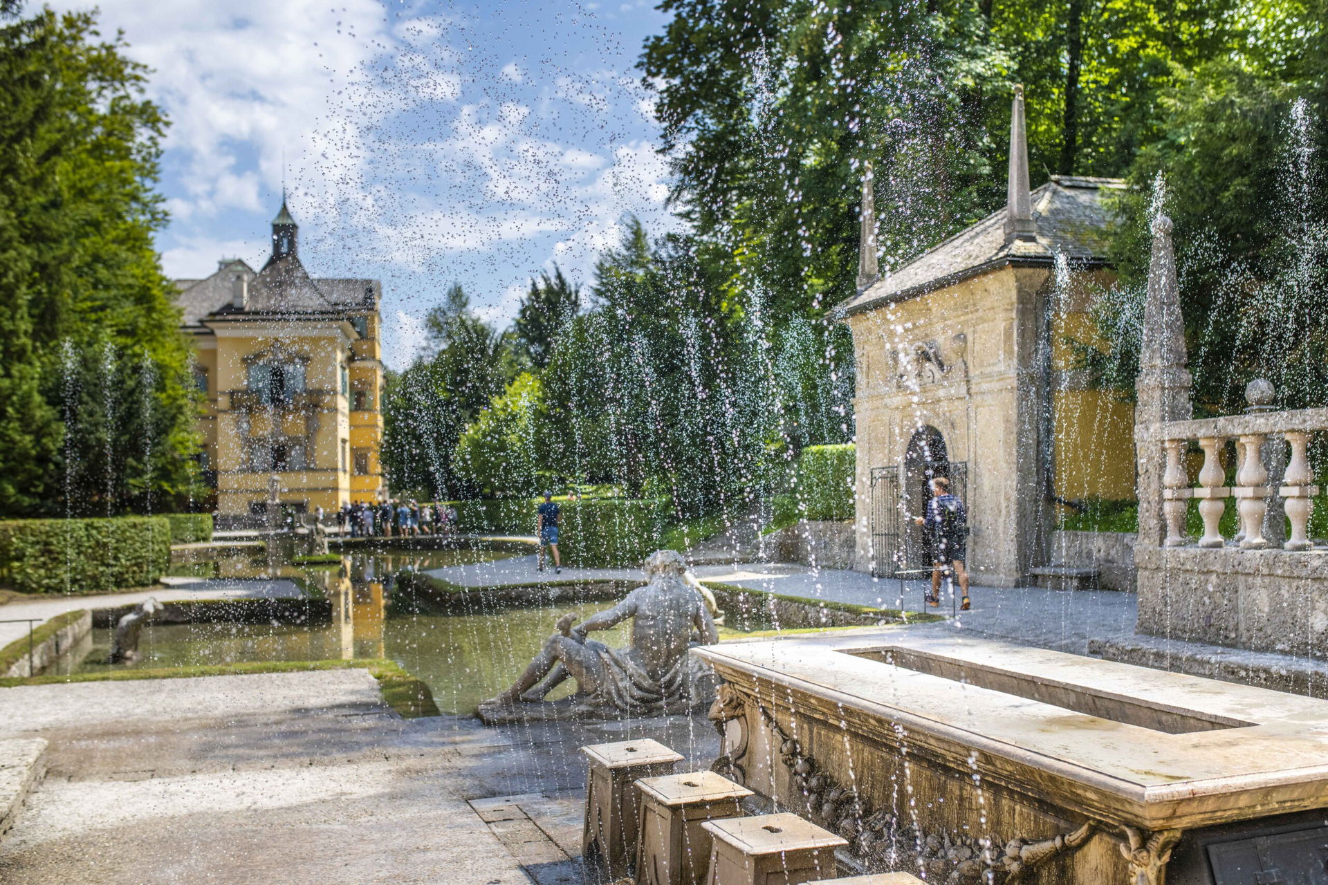 Brunnen mit Wasserstrahlen in Parkanlage bei Sonne.