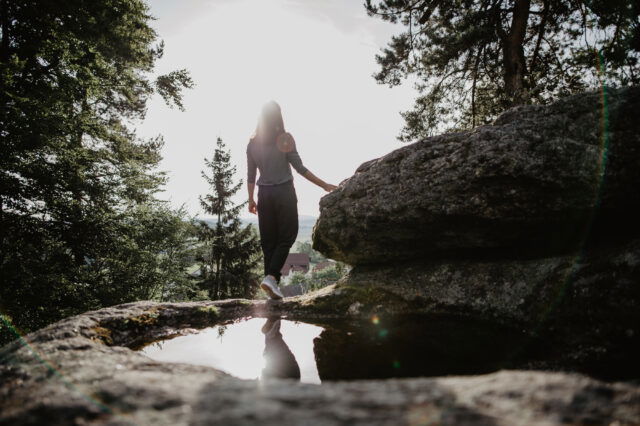 Eine Frau steht auf einem Granitfelsen und blickt in die Ferne