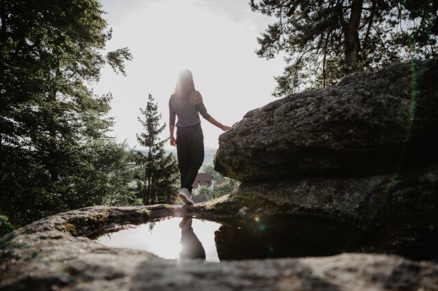 Eine Frau steht auf einem Granitfelsen und blickt in die Ferne