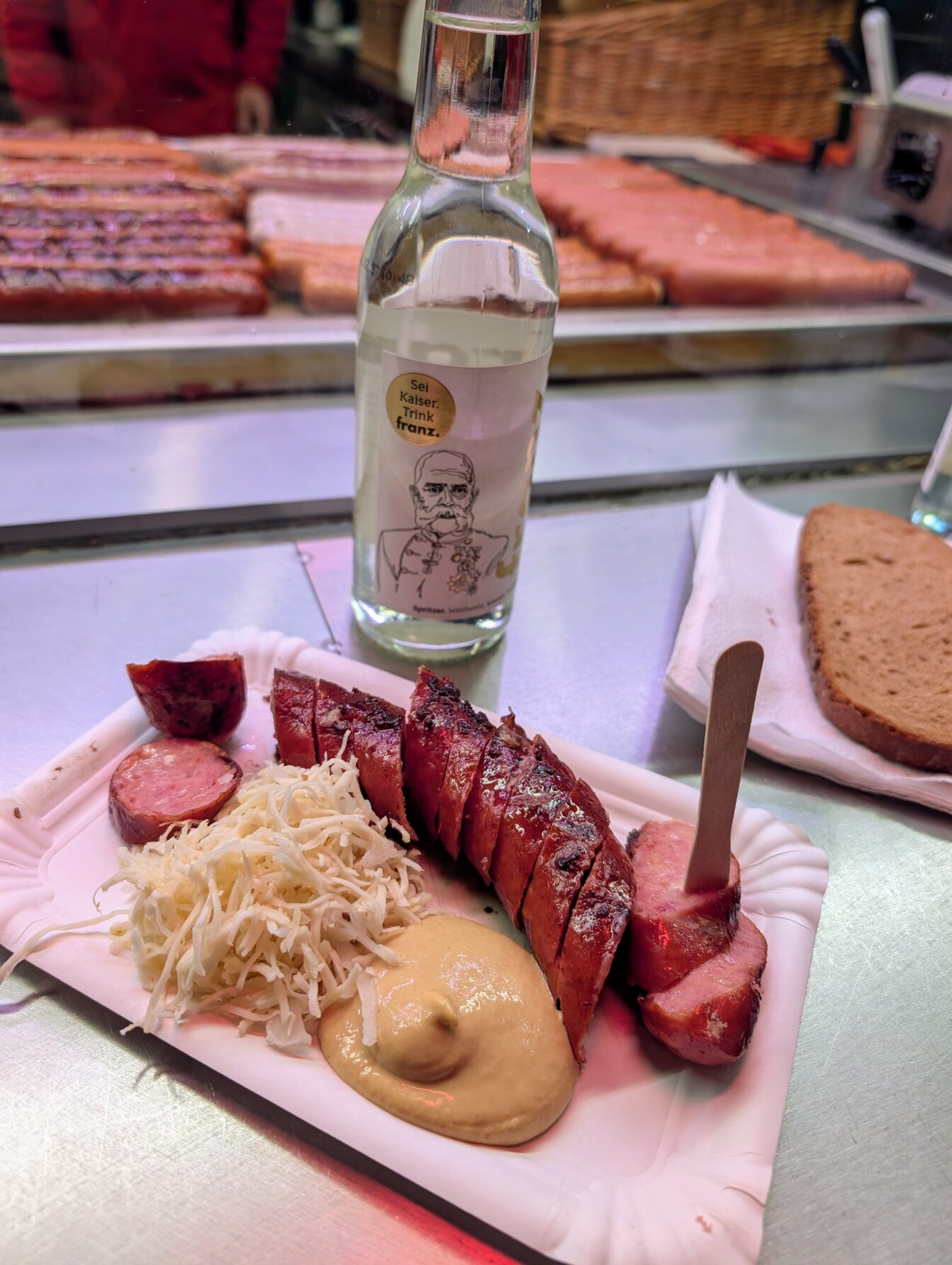 eine aufgeschnittene Käsekrainer mit Senf und Kren bei einem Würstelstand in Wien