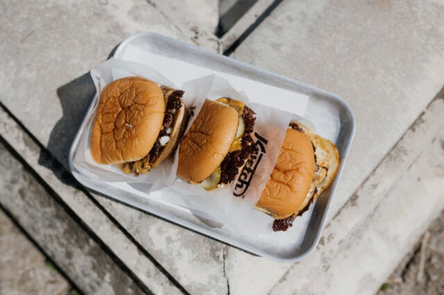 drei Smash Burger von Kvetch liegen auf einem Silbertablett in der Sonne