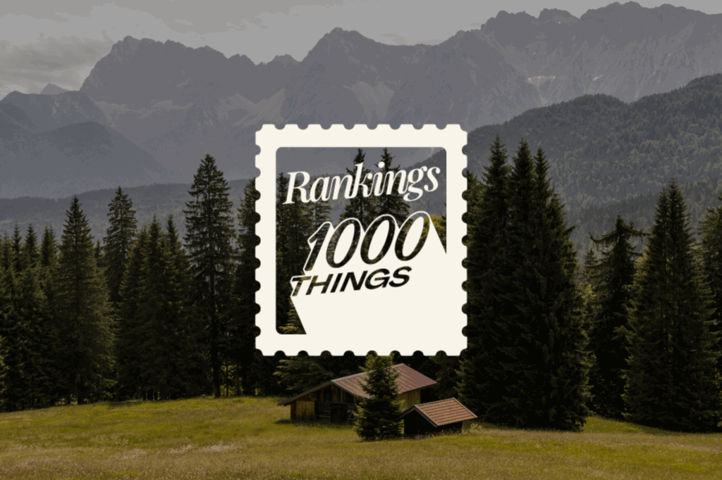 Hütte auf einer Wiese mit Bergen und Bäumen im Hintergrund