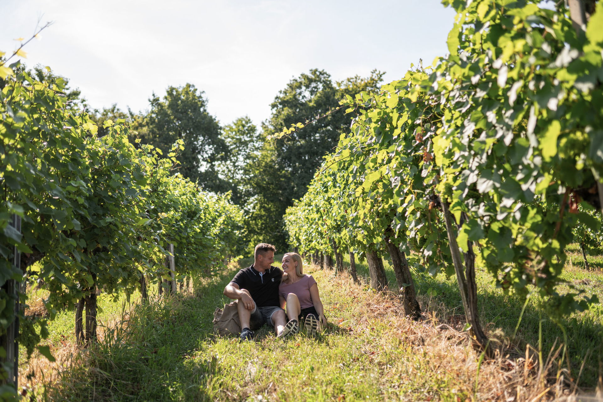 Ein Pärchen sitzt im sommerlichen Weingarten.