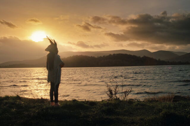 Juma Xipaia, Protagonistin des Dokumentarfilms "Yanuni - Die Stimme des Amazonas" steht bei Sonnenuntergang am Fluss Amazonas