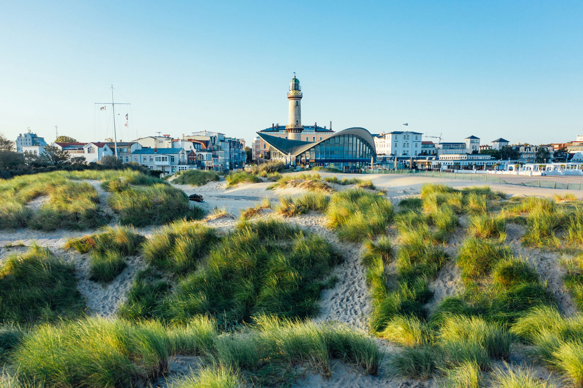 Blick über die Dünen auf den Leuchtturm und den Teepott im Seebad Warnemünde.