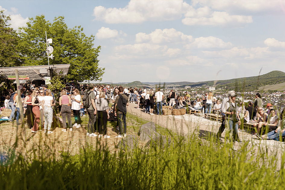 Mehrere Menschen stehen beim Weinfest AhrWeinWalk in den Weinbergen in Rheinland Pfalz, um Wein zu verkosten und zu plaudern.