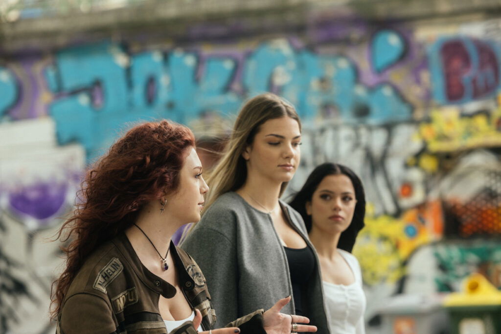 Drei Frauen spazieren vor Graffiti am Donaukanal