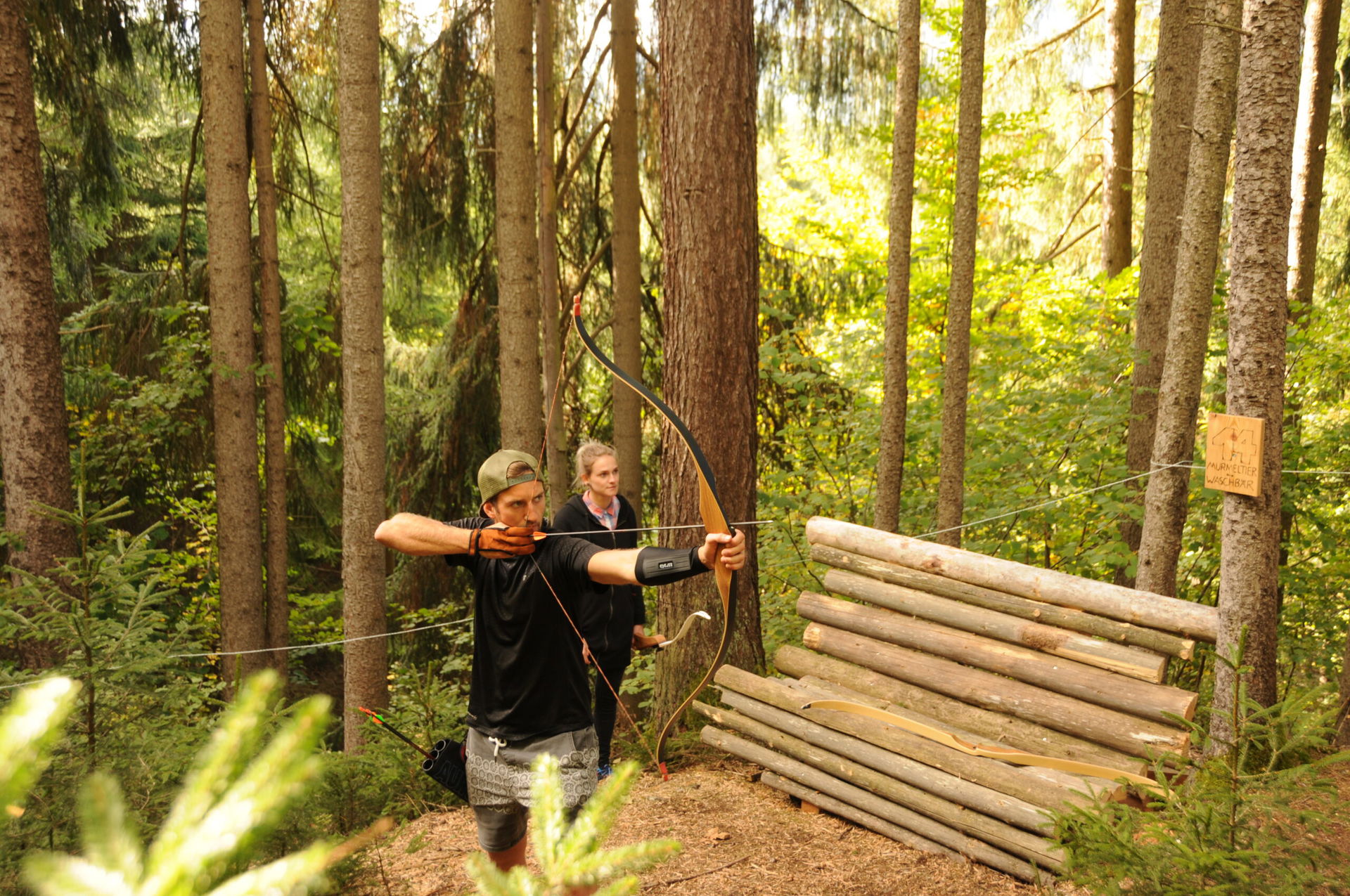 Zwei Personen beim Bogenschießen im Wald