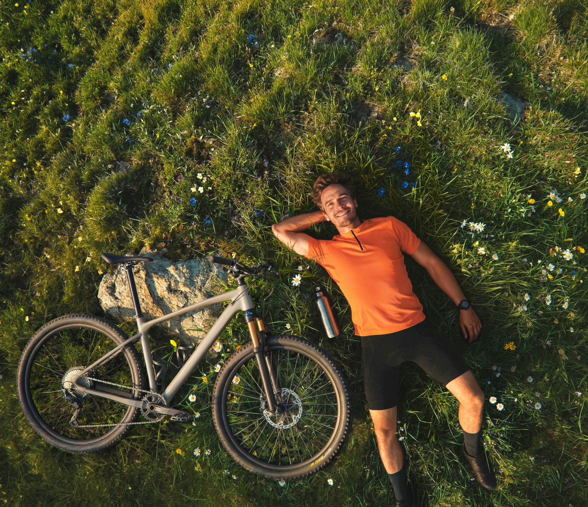 Mann liegt im Gras, neben im liegt ein Fahrrad