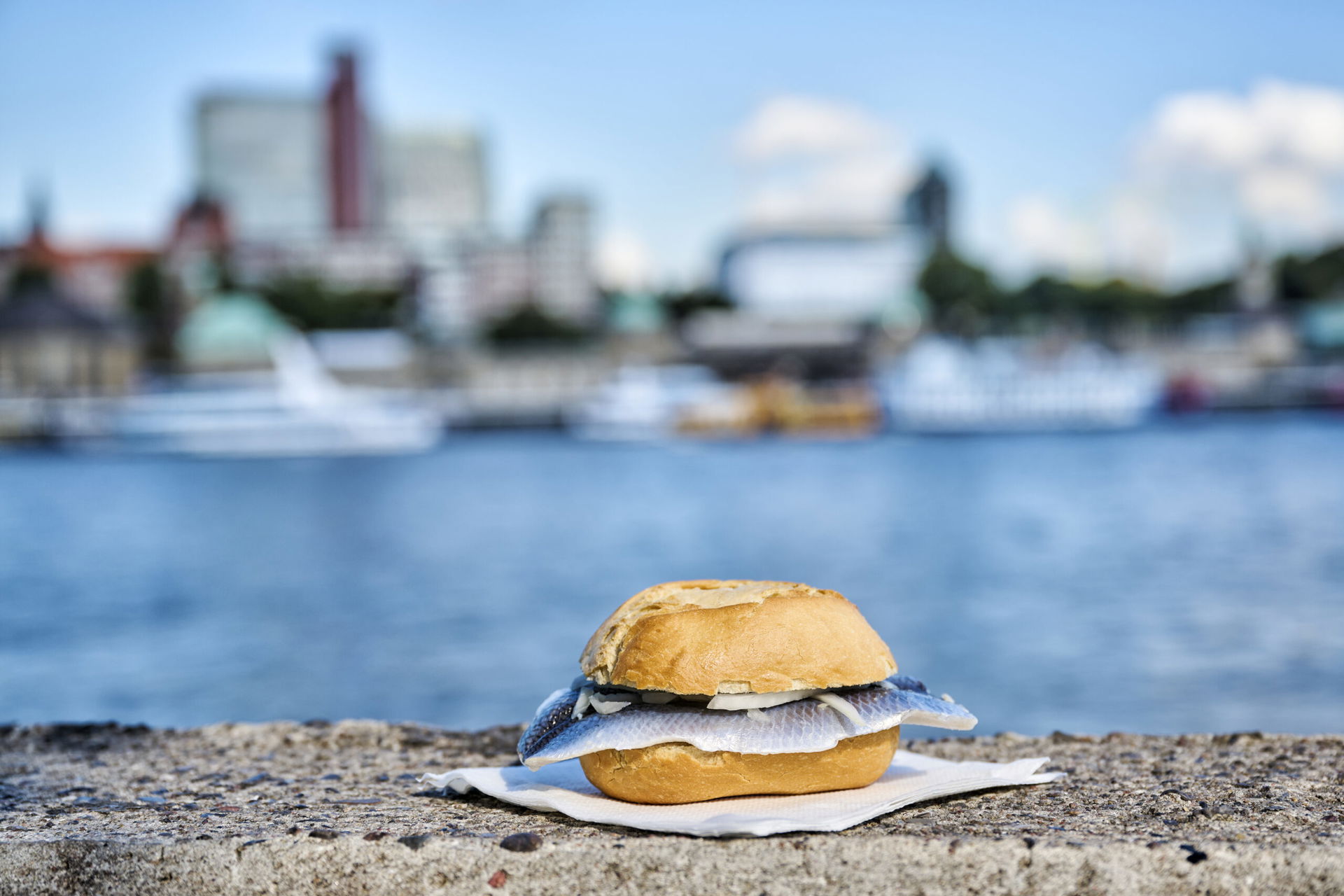 Ein Fischbrötchen liegt auf einer Mauer am Hafen in Hamburg