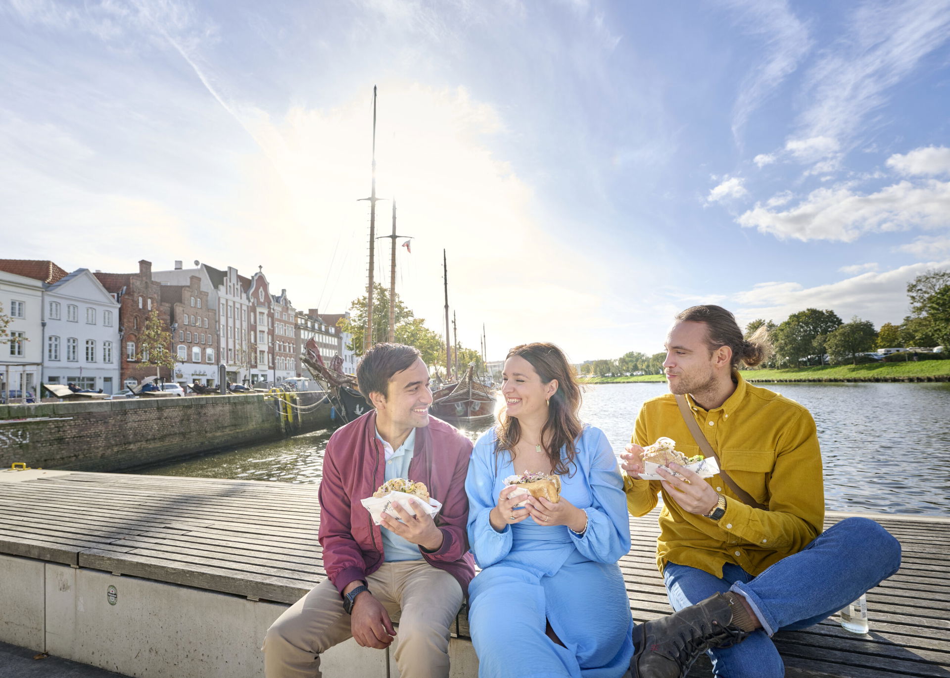 Freunde essen Fischbrötchen an der Trave in Lübeck