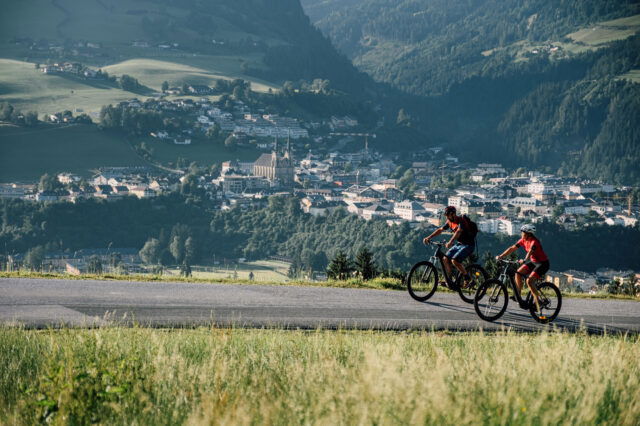 Zwei Radfahrer radeln an St. Johann in Salzburg vorbei