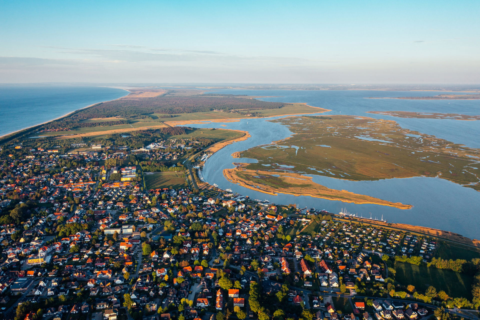 Vogelperspektive auf die Halblinsel Fischland-Darß-Zingst, man sieht Meer mit Mäander und Häuser. 