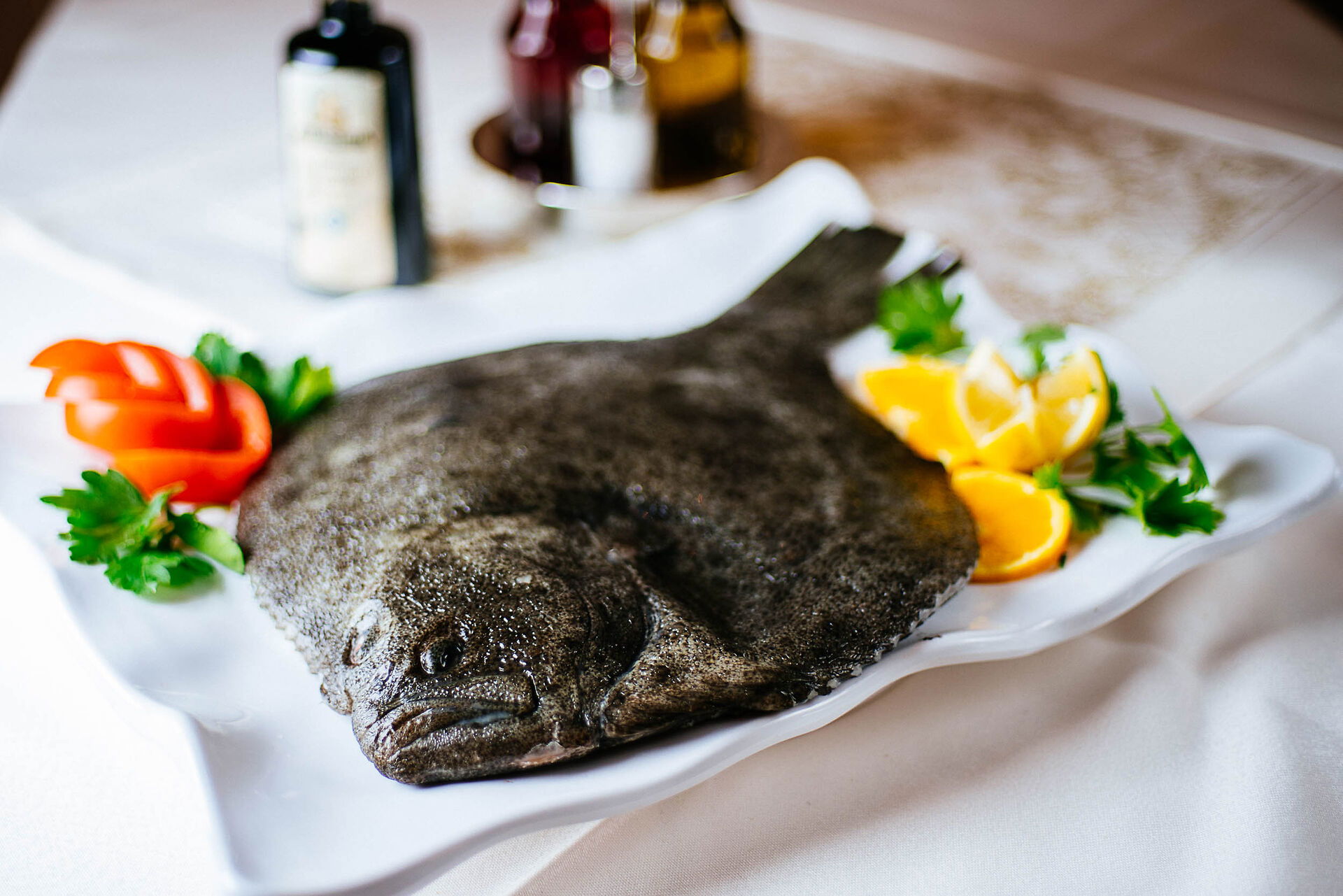 Ein Fisch liegt tot auf einem Teller: Mahlzeit! Rechts Zitronenscheiben, links deliziöse Tomate in Scheiben. In der Stadt Celle. 