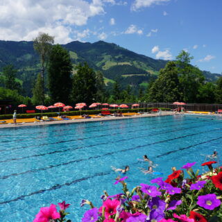 Schwimmbad im Sommer in St. Johann in Salzburg mit bunten Blumen im Vordergrund.