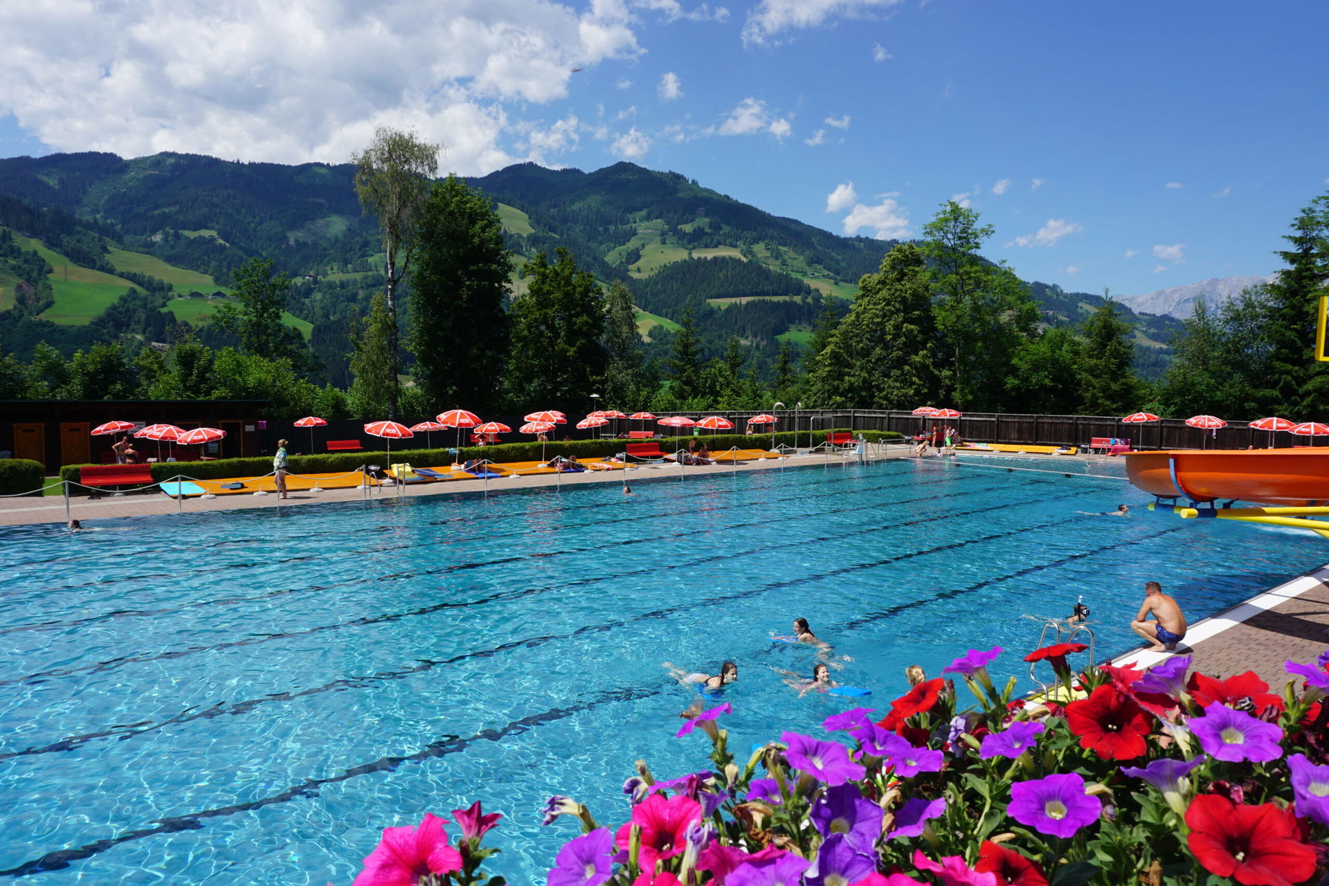 Schwimmbad im Sommer in St. Johann in Salzburg mit bunten Blumen im Vordergrund.
