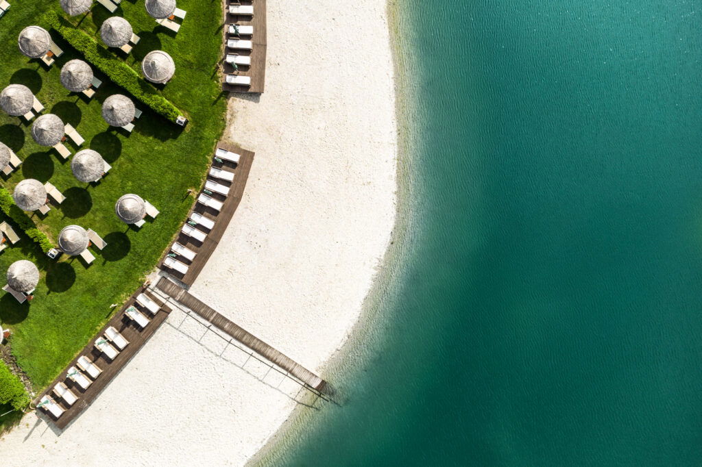Strandam See der St. Martins Therme & Lodge mit Sonnenschirmen und Steg.