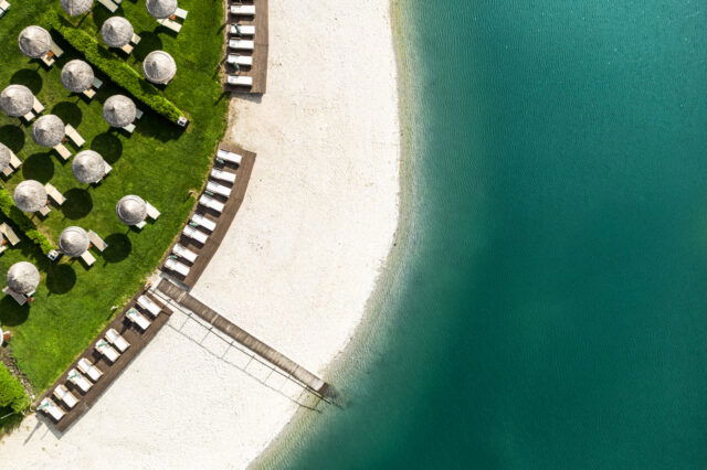 Strandam See der St. Martins Therme & Lodge mit Sonnenschirmen und Steg.