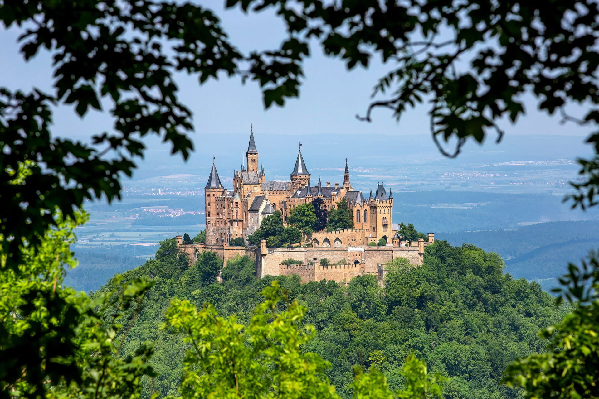 Eine märchenhafte Burg ist zu sehen, mit vielen Zinnen, hoch erhaben auf einem Berg. Es ist die Burg Hohenzollern in Baden-Württemberg.