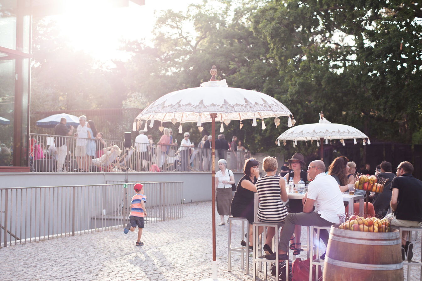 Menschen sitzen unter Sonnenschirmen im Garten des Belvederes in Wien beim Sommerfest