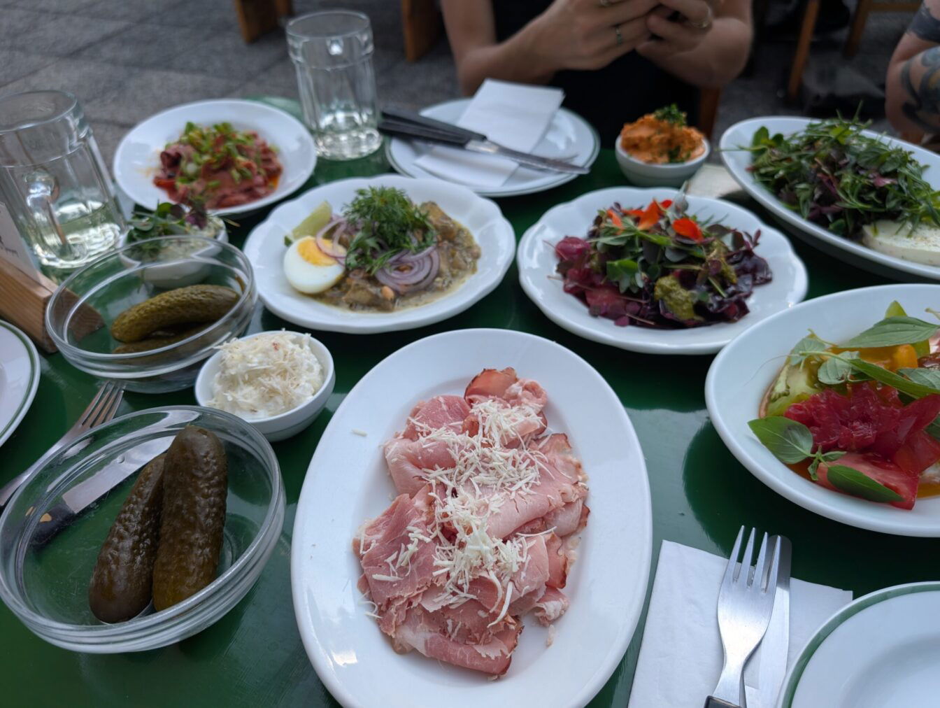 ein gefüllter Tisch mit verschiedenen Heurigen-Speisen im Gastgarten der Buschenschank in Residence in Wien Grinzing