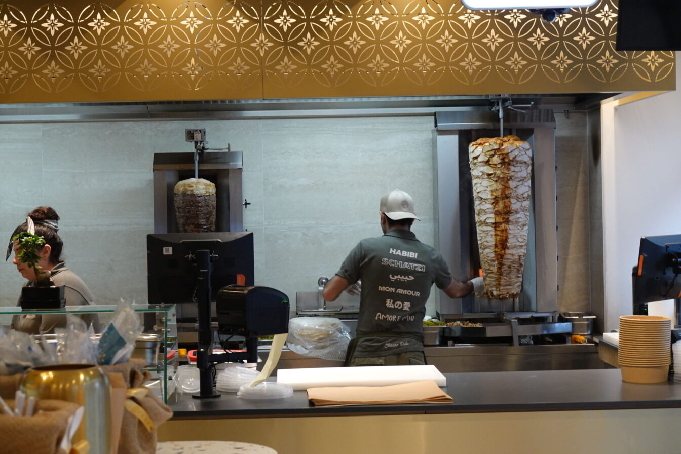 ein Angestellter des Restaurants Elissar Deli in Wien steht vor zwei Fleisch-Spießen