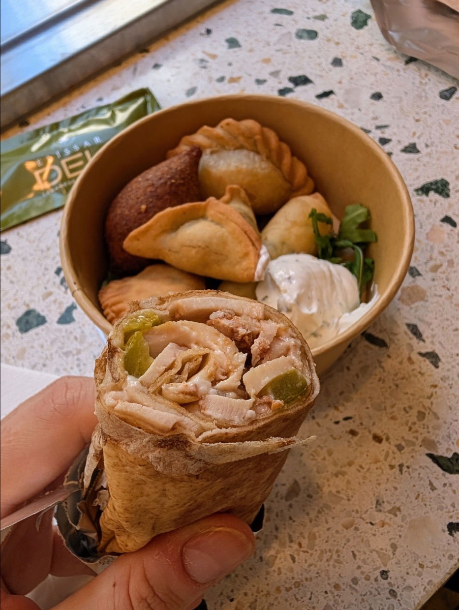 im Vordergrund ein Schawarma und im Hintergrund verschiedene Teigtaschen im Restaurant Elissar Deli in Wien
