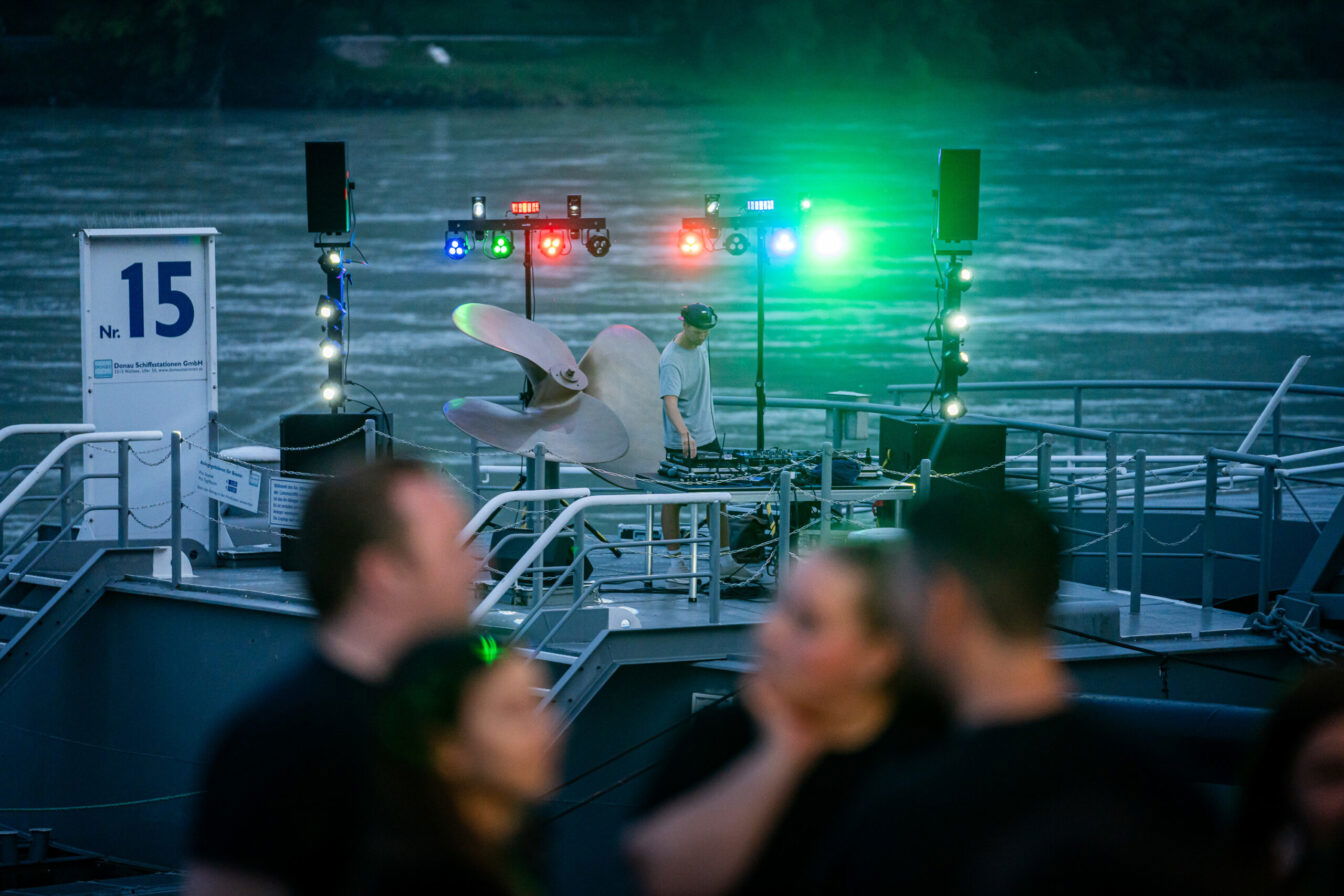 ein DJ steht vor seinem Mischpult vor dem Wasser bei der Donau Lounge in Spitz an der Donau in Niederösterreich