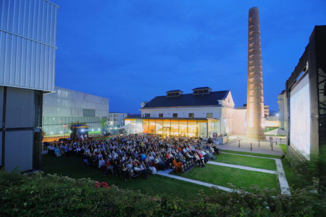 Menschen sitzen vor der Leinwand des abendlichen Sommerkinos beim Kesselhaus in Krems