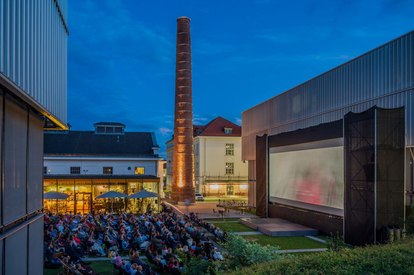 Menschen sitzen vor der Leinwand des abendlichen Sommerkinos beim Kesselhaus in Krems