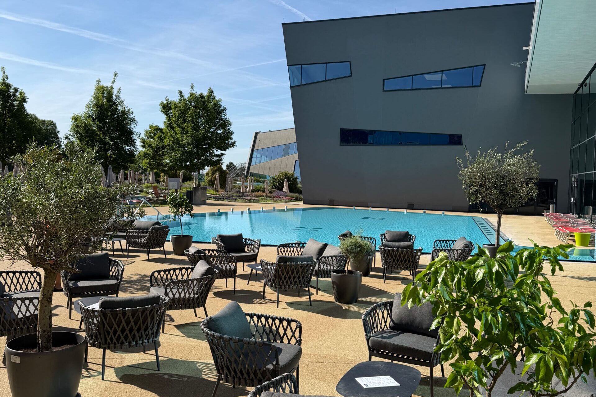 Gartenmöbel der Sommer Lounge in der Therme Wien stehen vor dem Swimming Pool